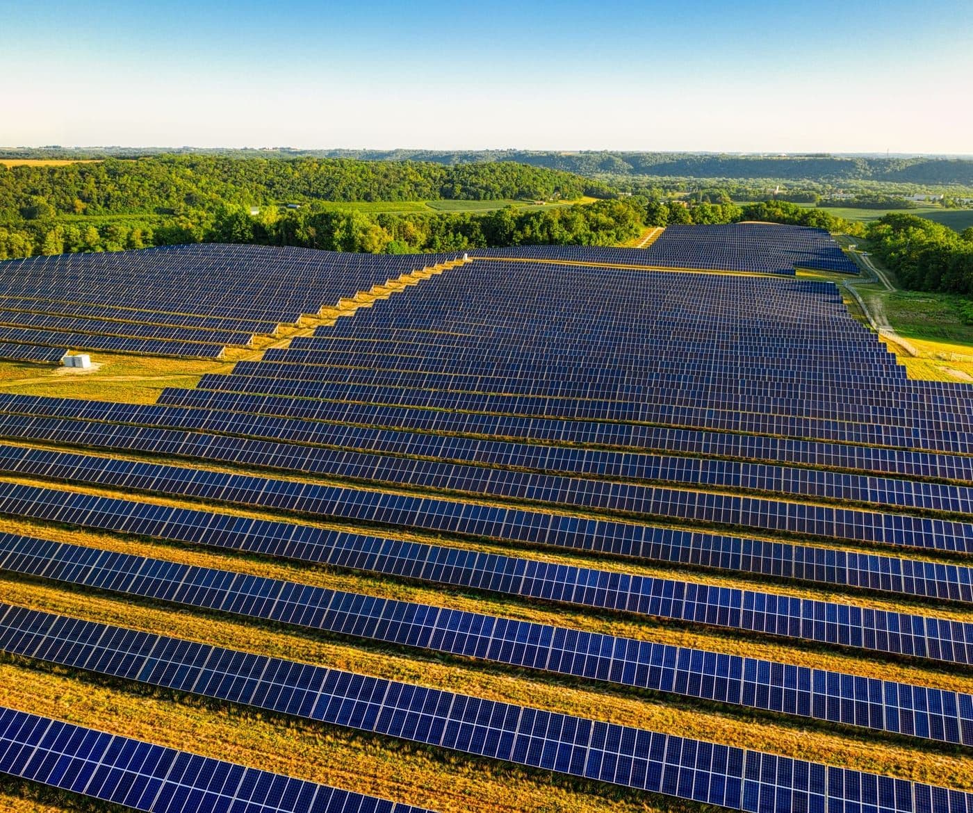 Gün batımında sıralar hâlinde uzanan güneş enerjisi santrali panelleri